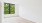 a room with a wood floor and a window with trees outside